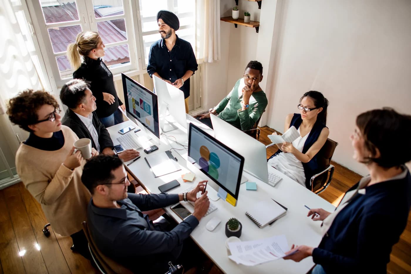 Creative team collaborating at a long desk with monitors