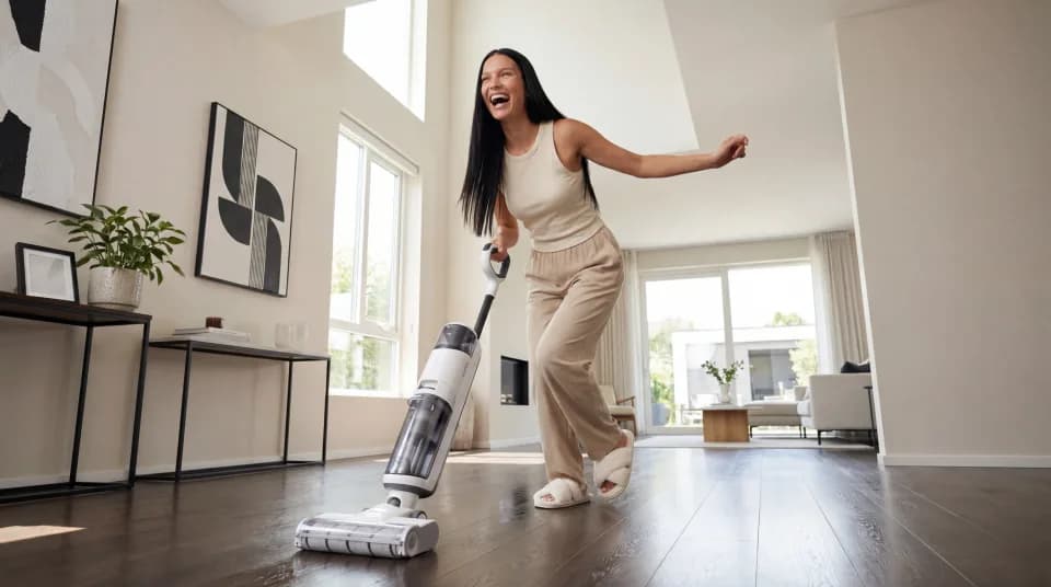 Woman laughing while vacuuming in a modern living room