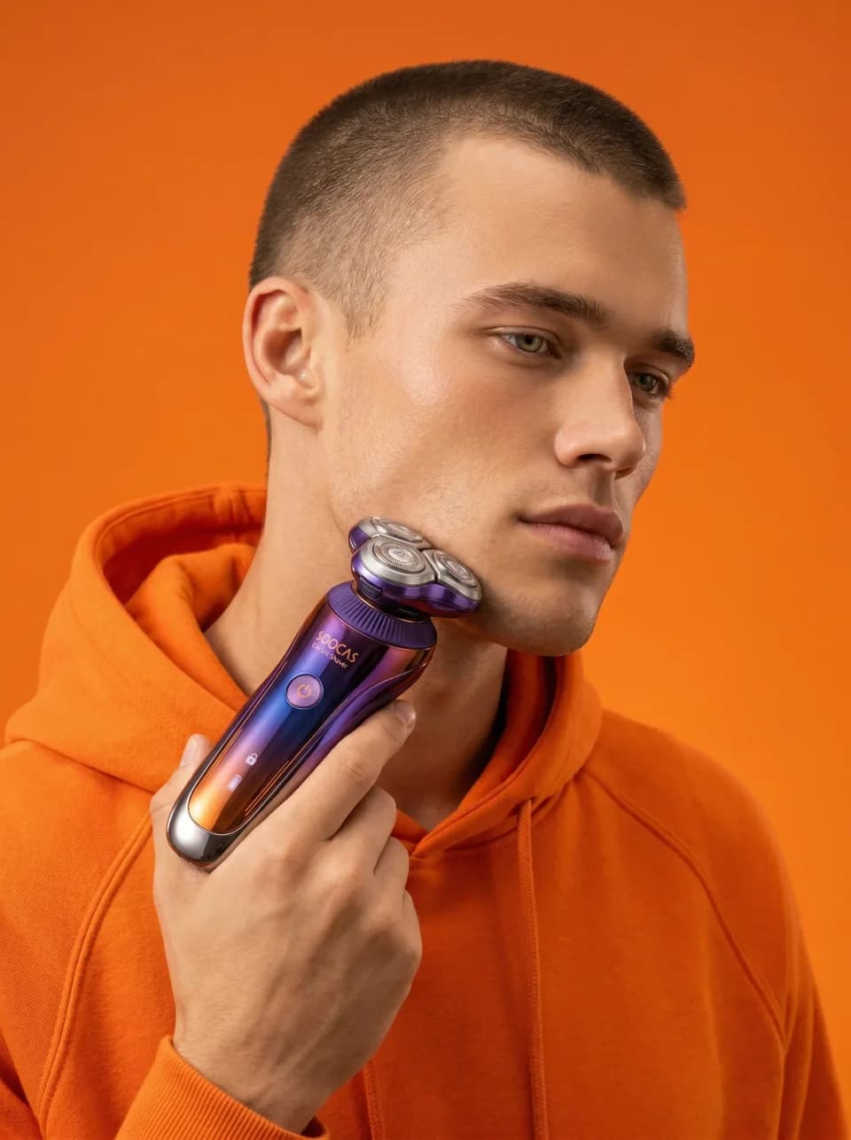 Man using an electric shaver against an orange background