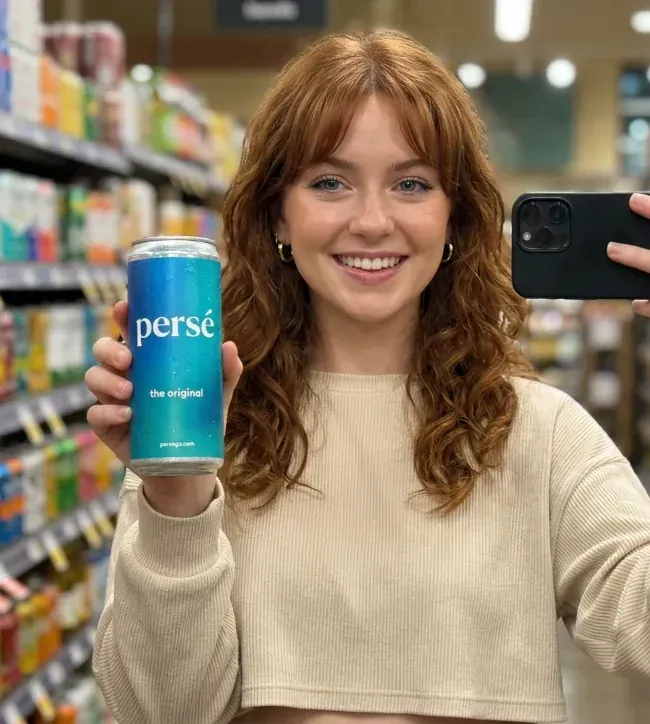 Creator filming UGC product content with a beverage can in a grocery store aisle