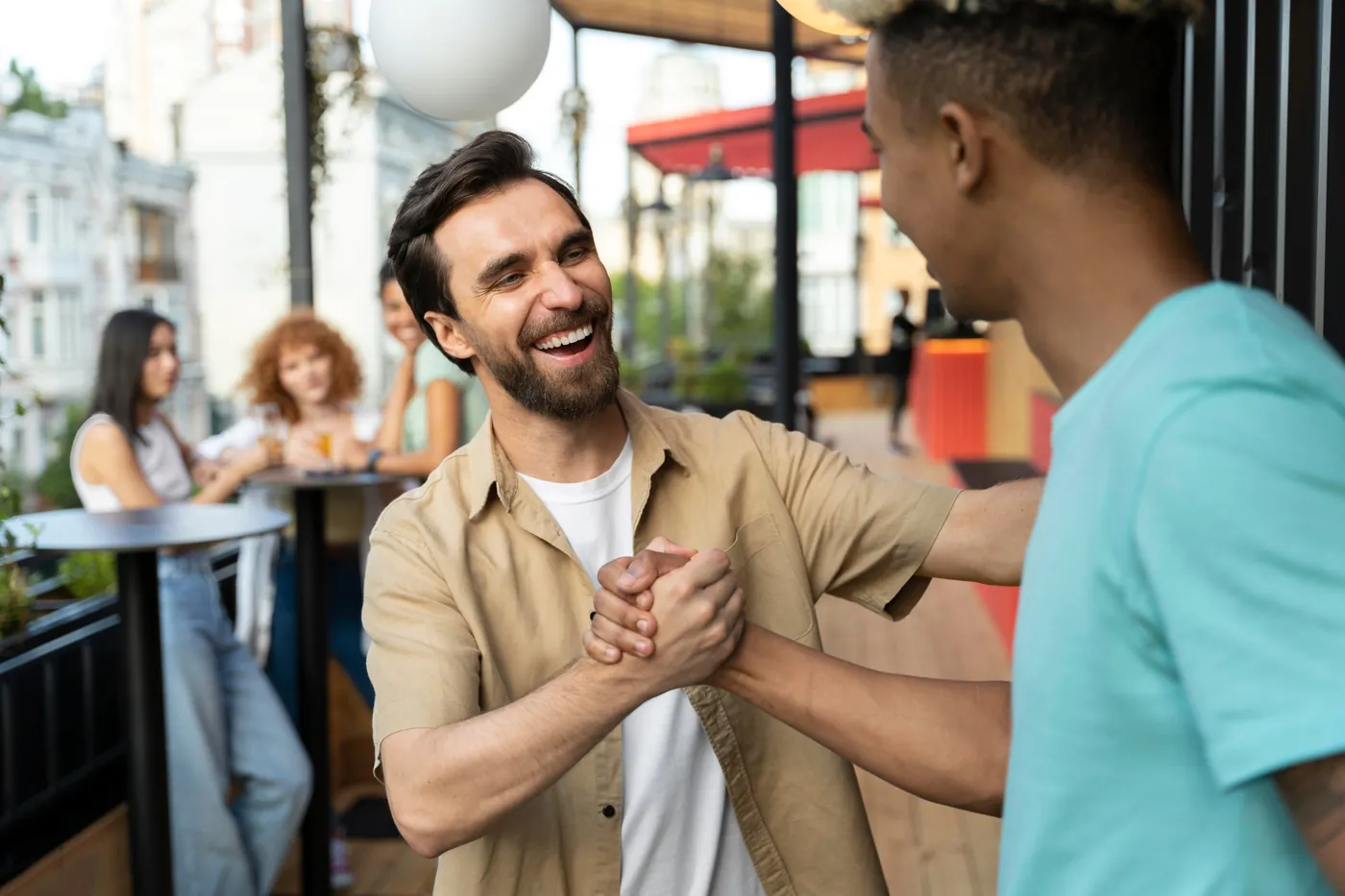 Two professionals shaking hands on an outdoor terrace, representing partnership.