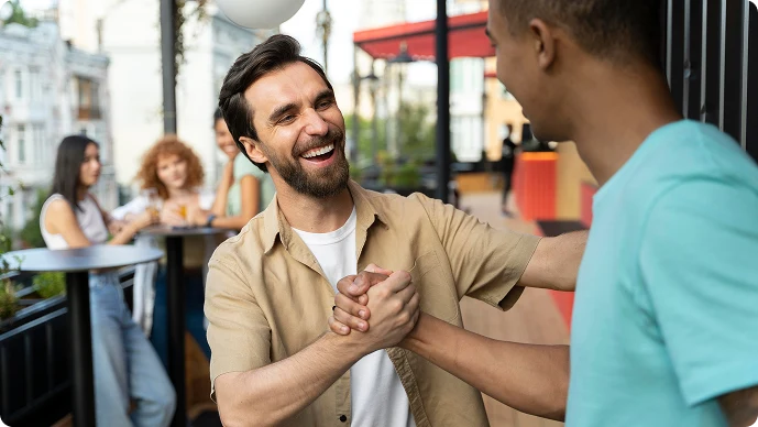 Two professionals shaking hands on an outdoor terrace, representing partnership.