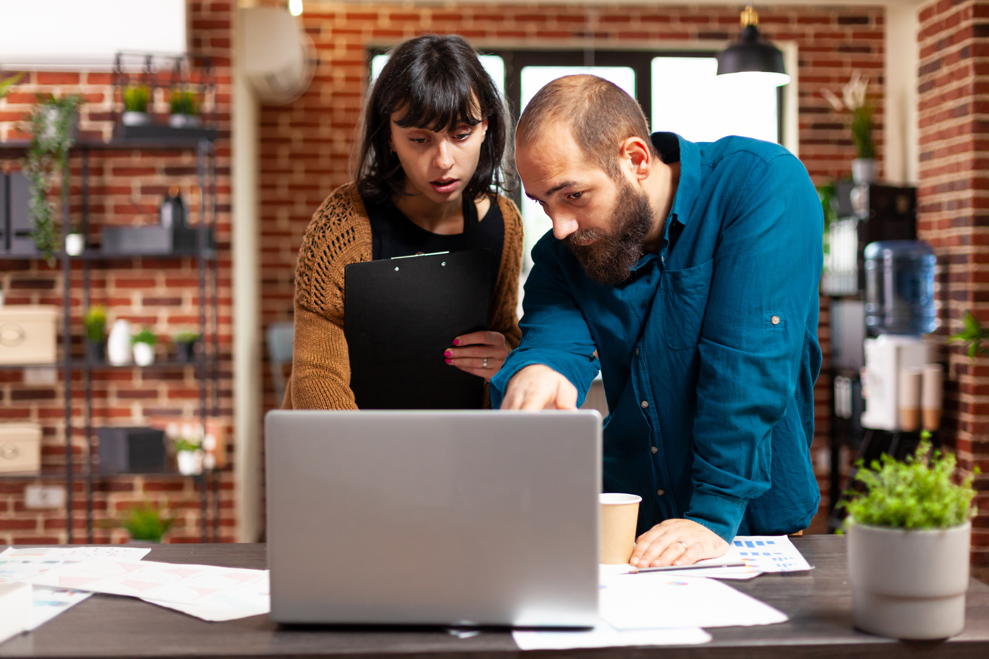 Two teammates collaborating over a laptop in an office setting.