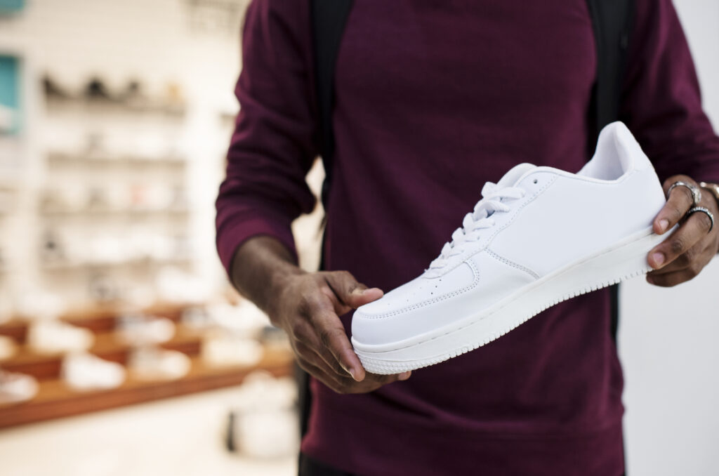 African man holding a white sneaker famous footwear outlet