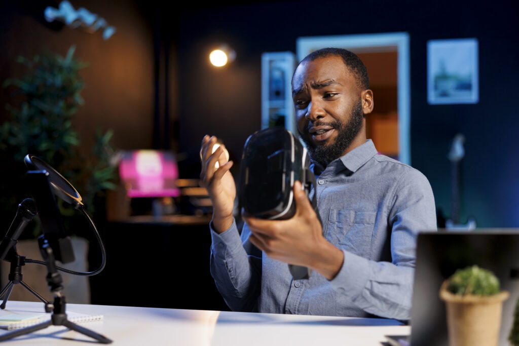 Content creator in a studio reviews a VR headset to camera with mic and phone rig, filming a product video using Ai video editing for social media.